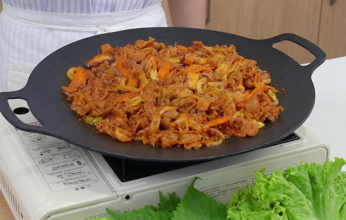 완성된 제육볶음 위에 통깨를 솔솔 뿌리는 근접 촬영