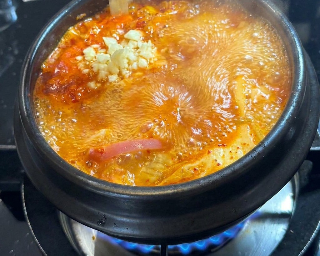 끓는 찌개 한가운데에 다진 마늘을 넣는 모습.