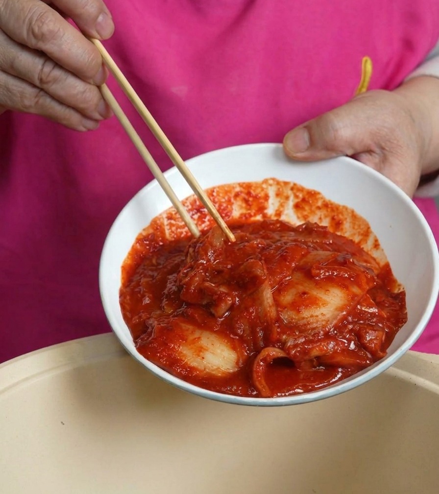 빨간 양념이 잘 밴 먹음직스러운 신김치를 냄비에 넉넉히 넣는 모습