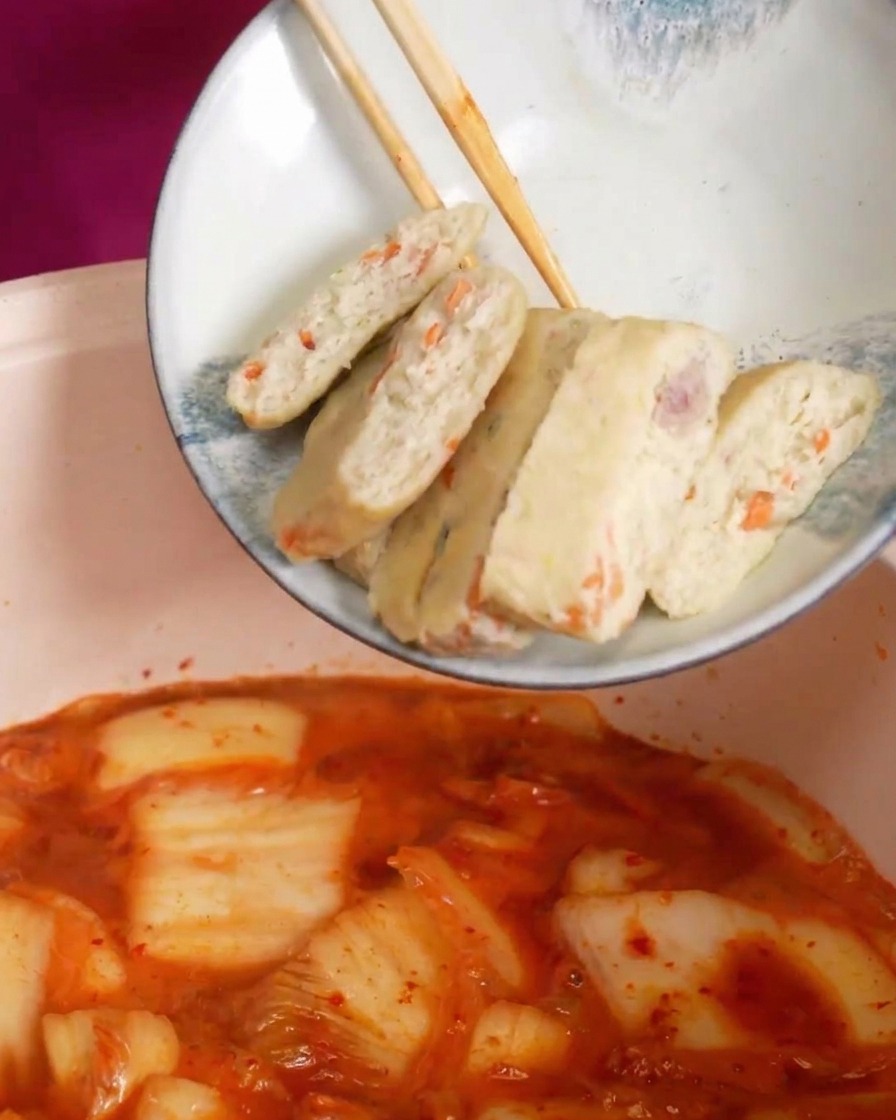 보글보글 끓어오르는 빨간 찌개 국물에 썰어놓은 어묵을 넣는 장면