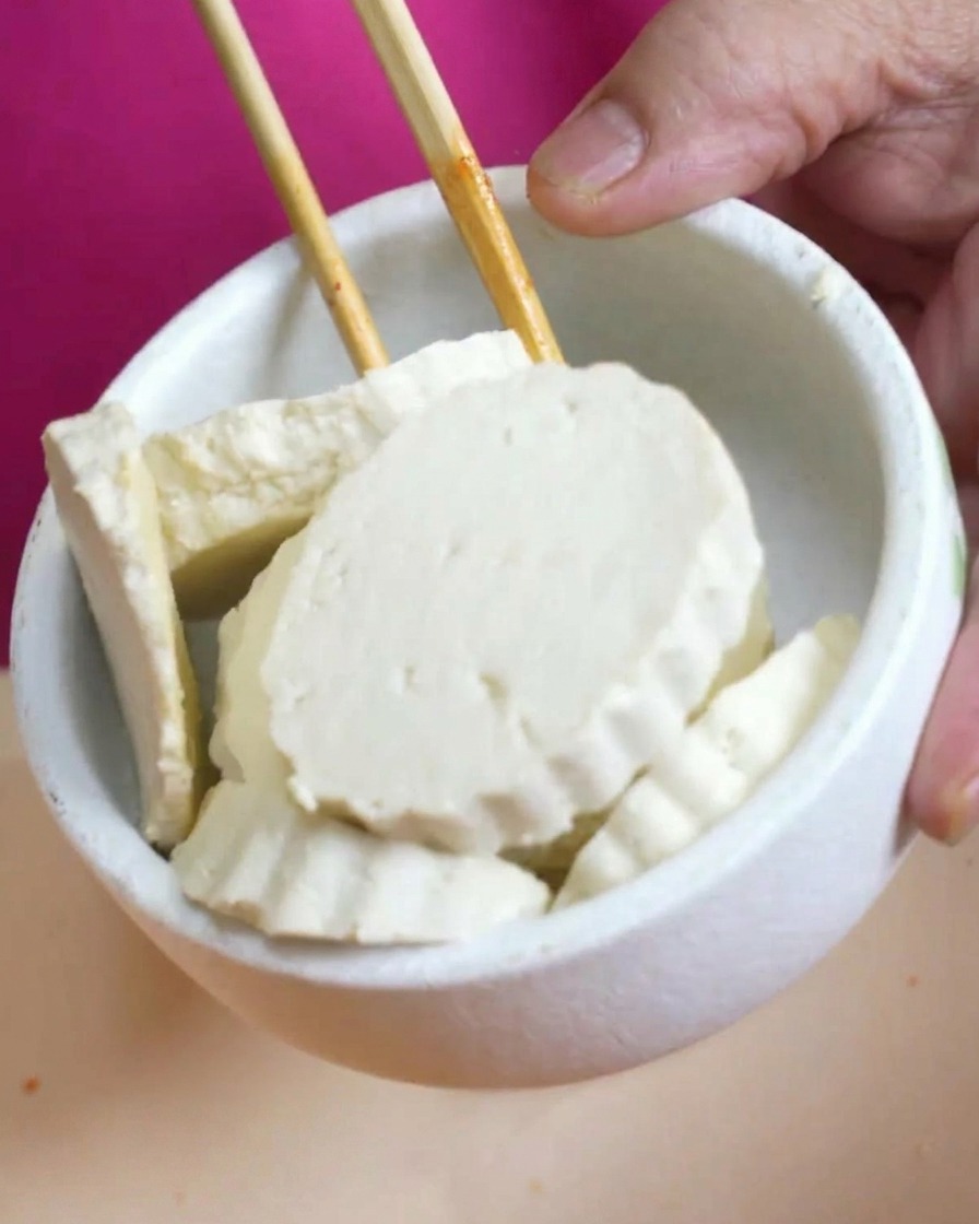 뽀얀 두부 슬라이스를 끓는 김치찌개 위에 조심스럽게 올리는 모습