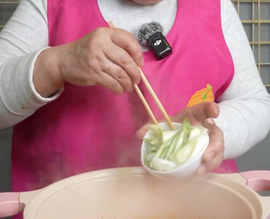송송 썬 초록색 대파를 붉은 찌개 위에 고명으로 뿌리는 모습