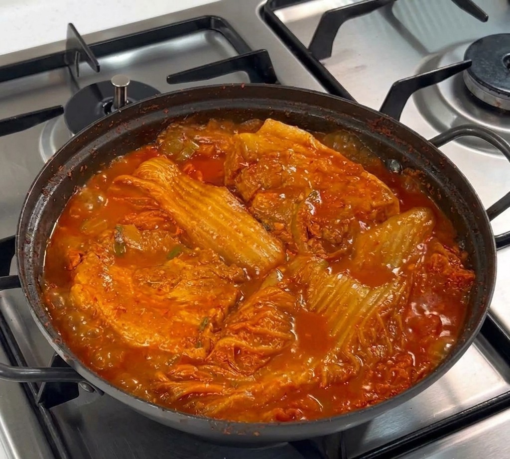 검은색 냄비 바닥에 채 썬 양파를 깔고 그 위에 생 통삼겹살 두 덩이를 올린 모습.