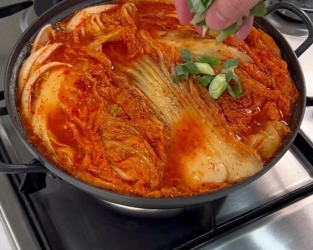빨간 국물이 담긴 냄비 위에 어슷 썬 대파를 한 줌 뿌려 올린 모습.