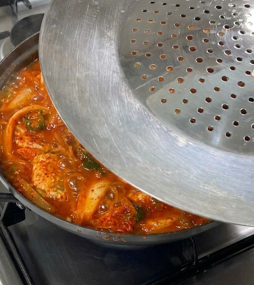 보글보글 끓기 시작한 김치찜 냄비 위로 뚜껑을 닫는 모습.