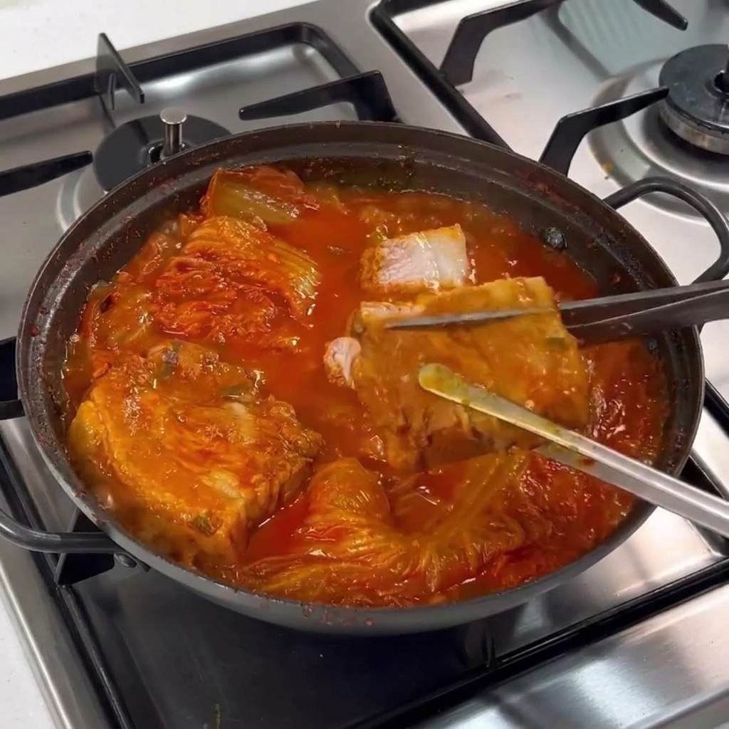 잘 익은 통삼겹살을 집게로 들어올려 가위로 먹기 좋게 자르는 모습.