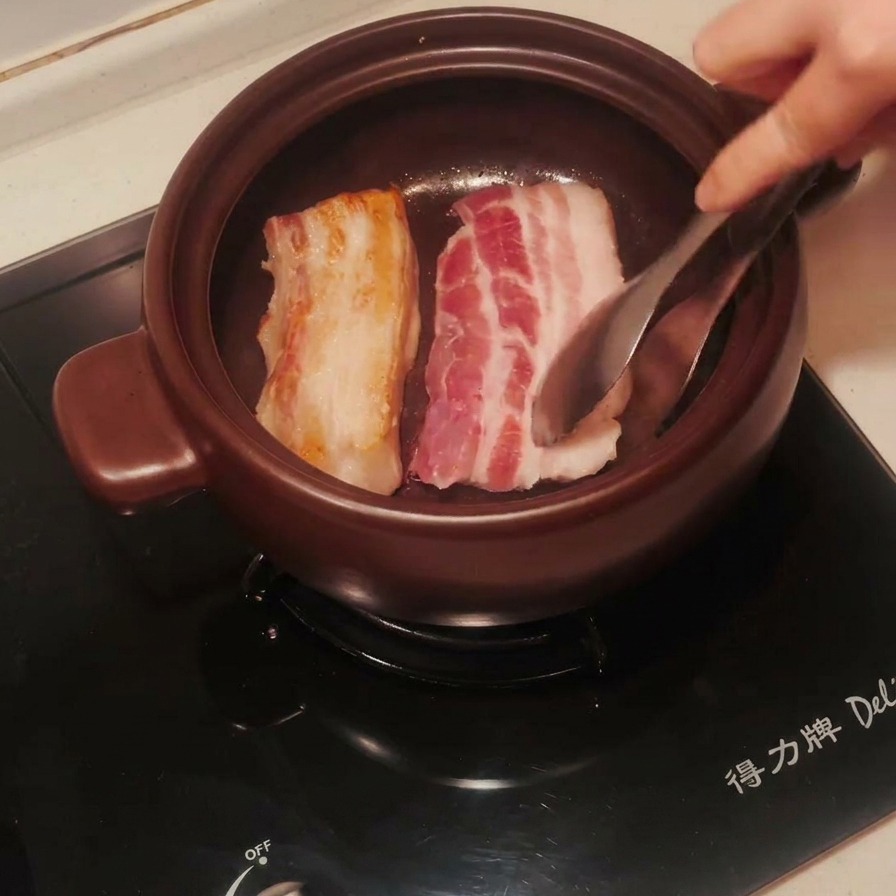 뚝배기 안에서 노릇하게 구워진 삼겹살을 뒤집는 모습