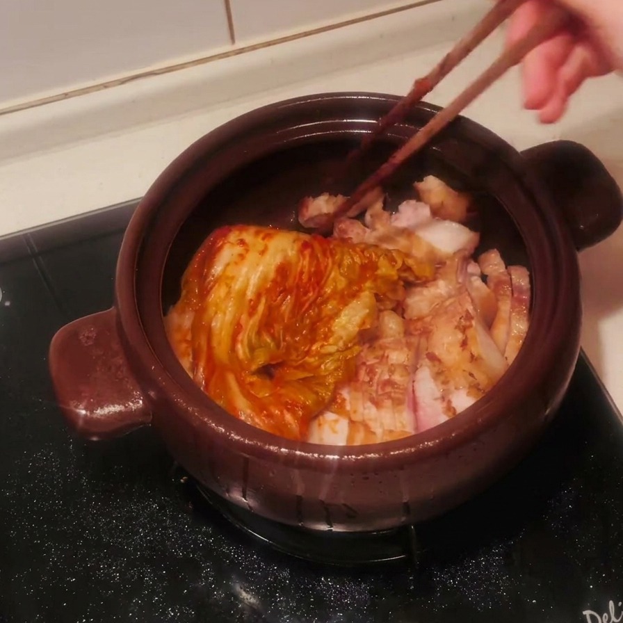 잘 익은 신김치를 삼겹살 위에 넉넉히 올리는 모습