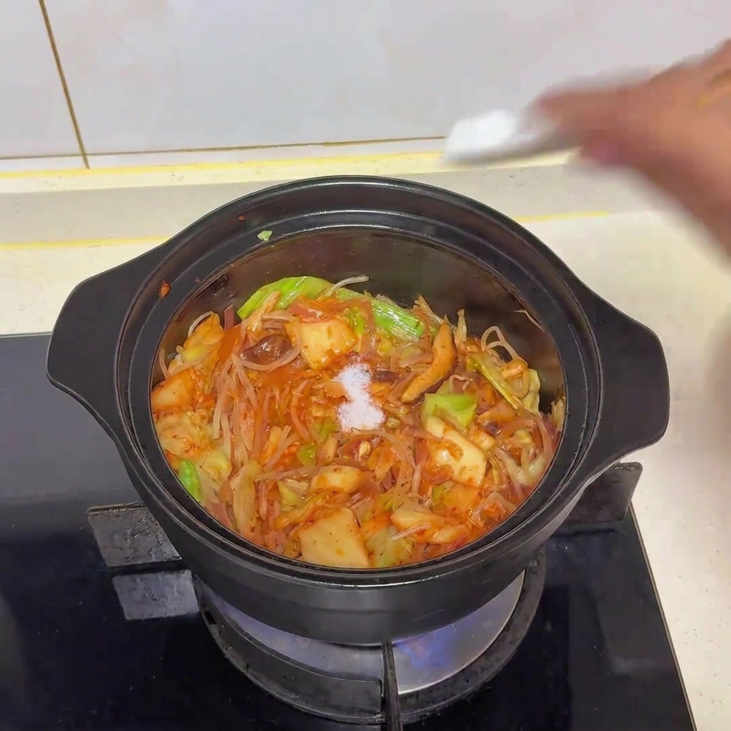 냄비 안의 재료에 소금을 한 꼬집 뿌리는 모습
