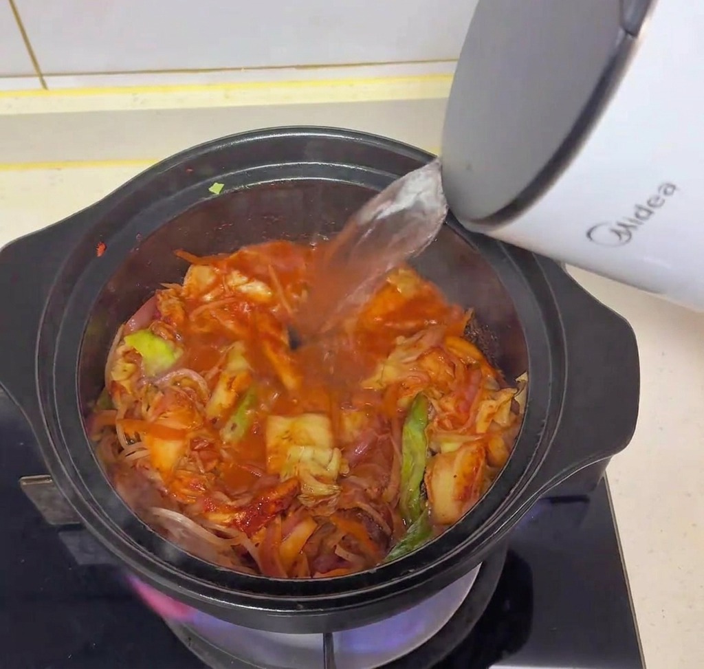 포트에서 뜨거운 물을 냄비에 붓는 모습