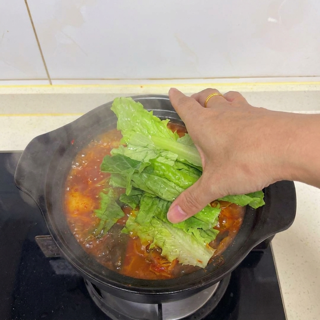 끓는 찌개 위에 상추 잎을 올리는 모습