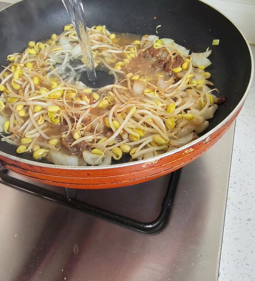 된장과 콩나물이 담긴 팬에 맑은 물이 부어지고 있는 모습