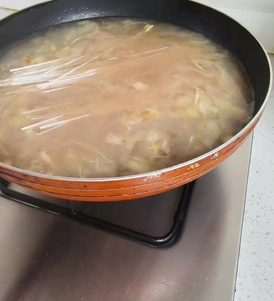끓는 된장찌개 국물 속에 마른 당면을 넣고 있는 손