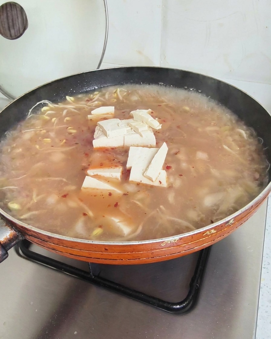 빨간 국물이 도는 찌개 위에 올려진 하얀 두부 큐브들