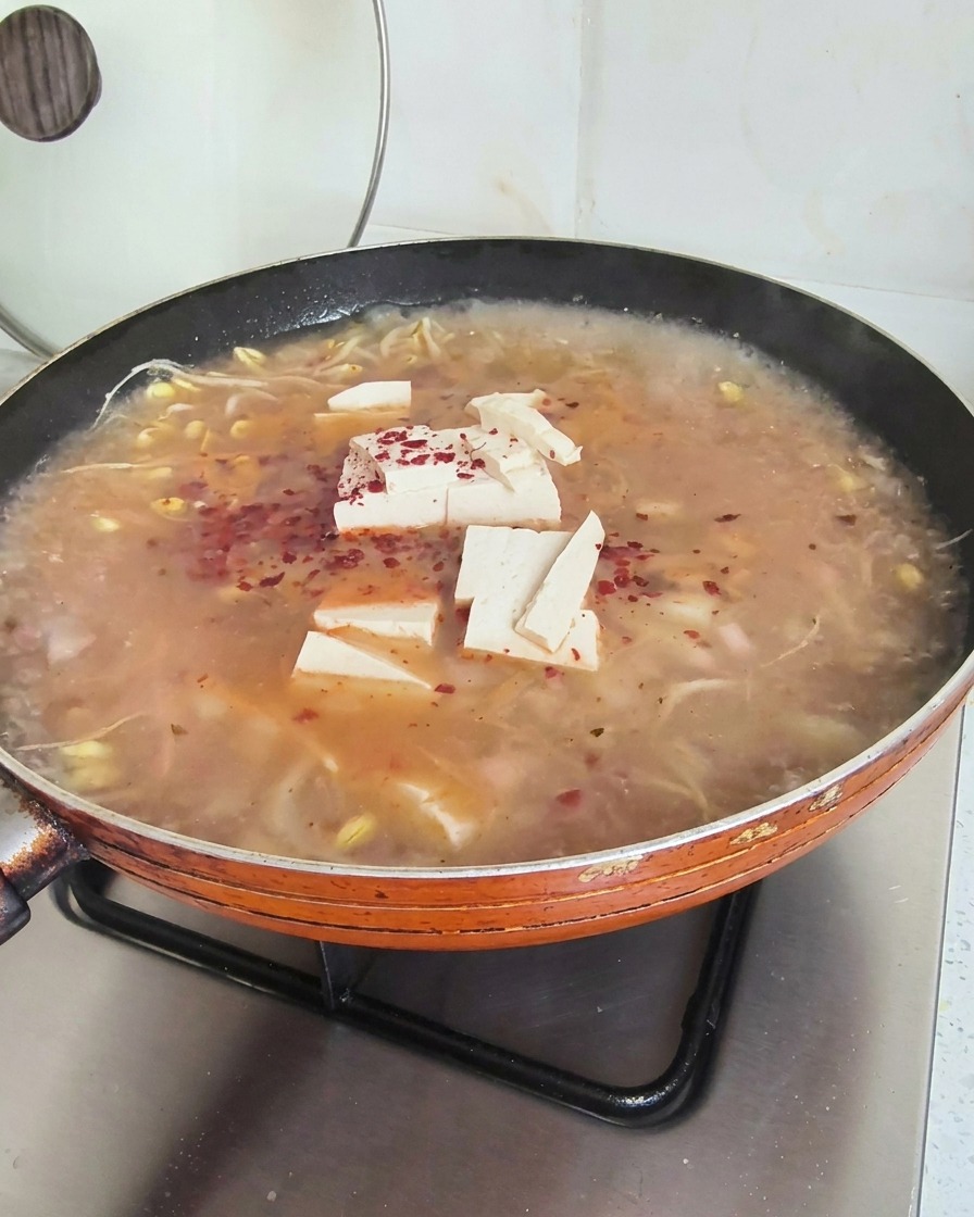 보글보글 끓는 두부 된장찌개 위에 뿌려진 붉은 고춧가루