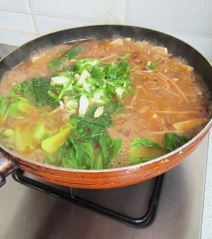 다진 마늘, 대파, 청양고추가 고명으로 올라간 된장찌개의 마지막 조리 장면