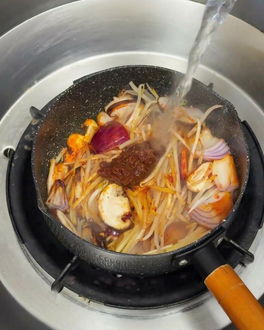 양념된 재료들이 잠기도록 뜨거운 물을 부어 국물을 만드는 과정.