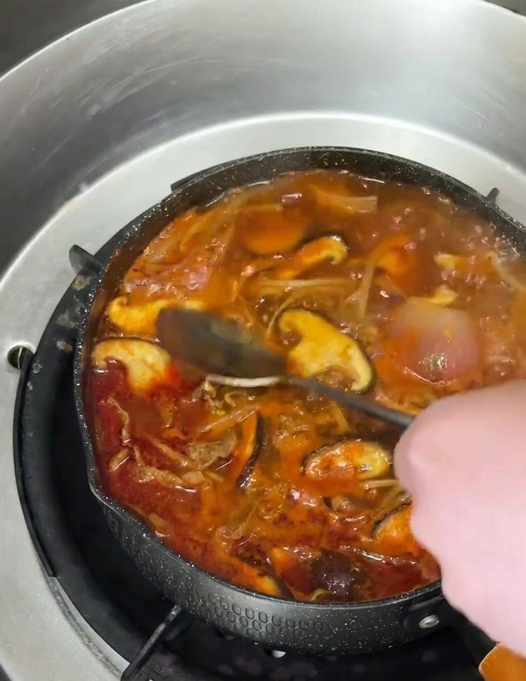 완성된 국물 위로 맑은 참기름을 한 스푼 떨어뜨려 윤기와 향을 더하는 과정.