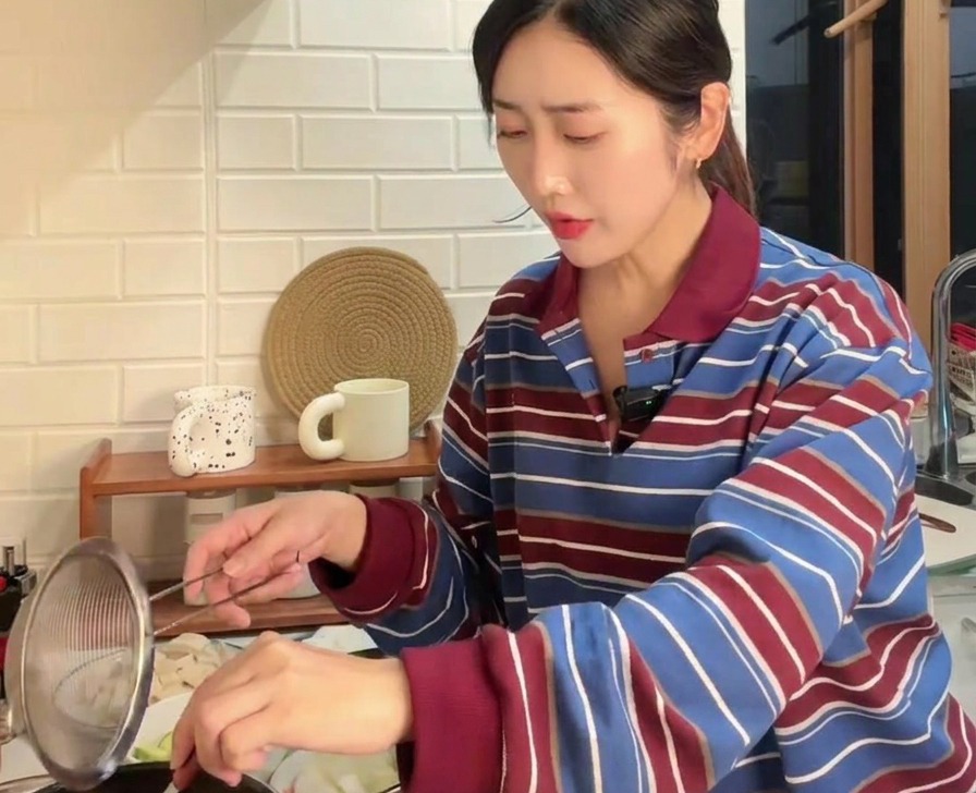 끓는 물 위에 체를 받치고 숟가락으로 된장을 곱게 풀고 있는 모습
