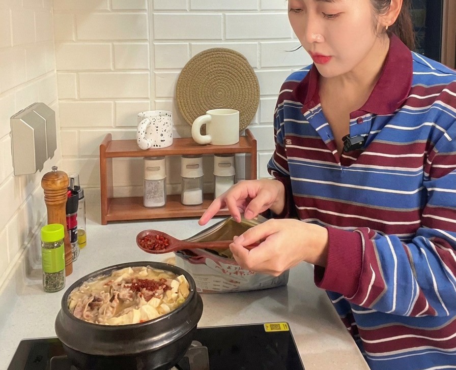 소고기와 채소가 가득한 찌개 위에 붉은 고춧가루를 뿌려 색감을 내는 모습