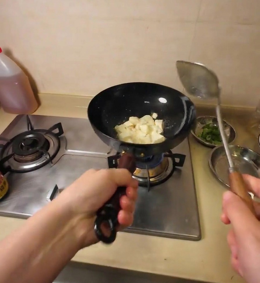 금속 조리 도구로 기름에 지글거리는 두부를 먹기 좋은 크기로 자르는 모습