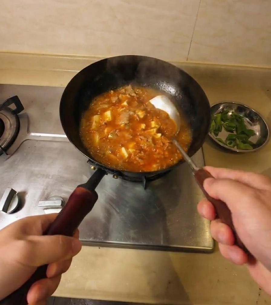 보글보글 끓는 소고기 두부 찌개를 저어 국물이 걸쭉해지는 모습