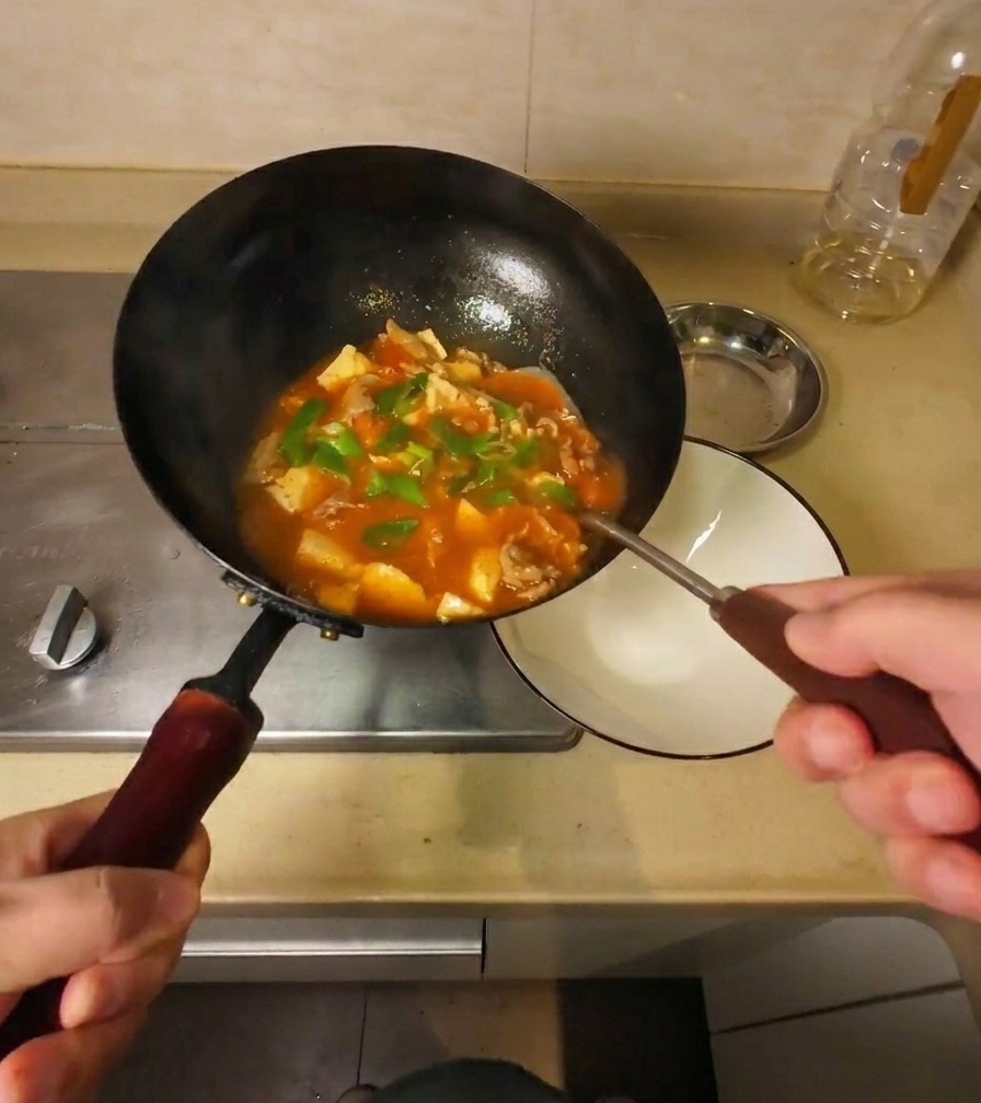 완성된 찌개를 웍에서 하얀 그릇으로 옮겨 담는 모습