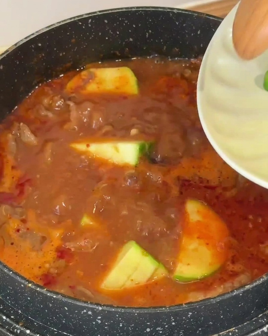 보글보글 끓는 국물에 썰어둔 애호박을 넣는 모습