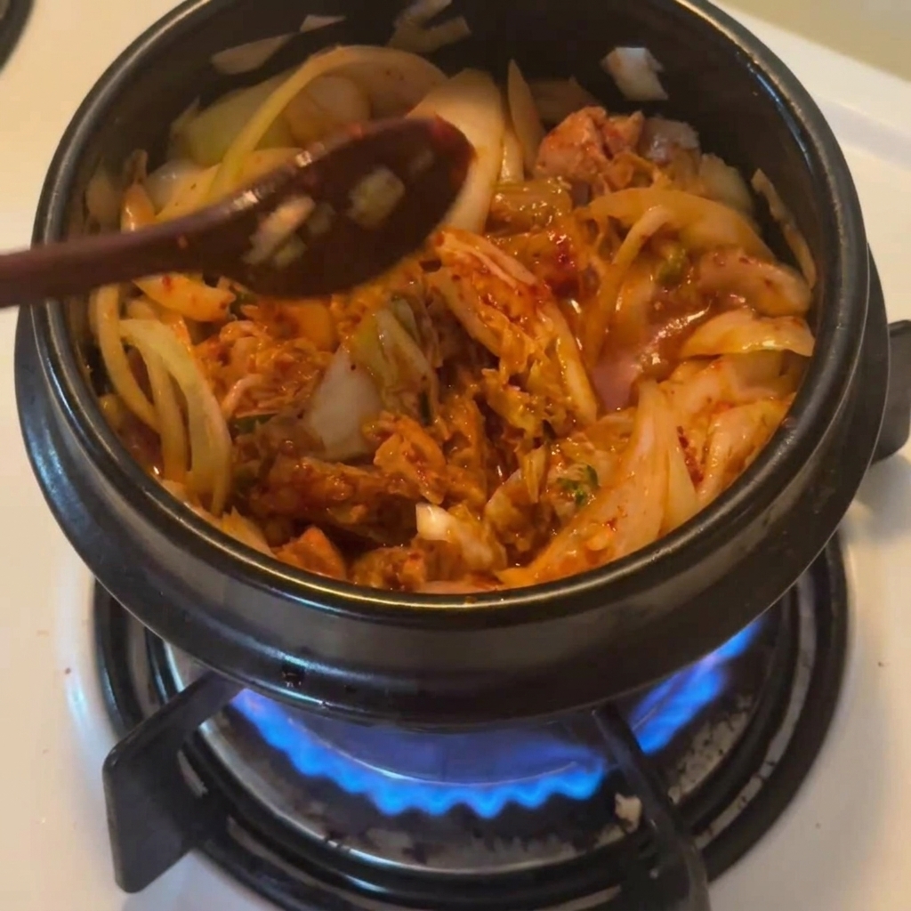 붉은 고춧가루를 찌개 베이스 위에 뿌려 색감을 내는 모습.