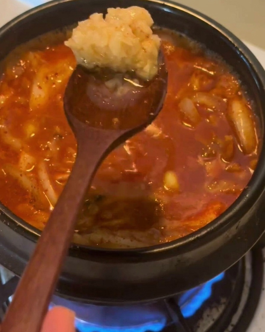 끓고 있는 찌개 국물 위에 다진 마늘 한 큰술을 올리는 모습.