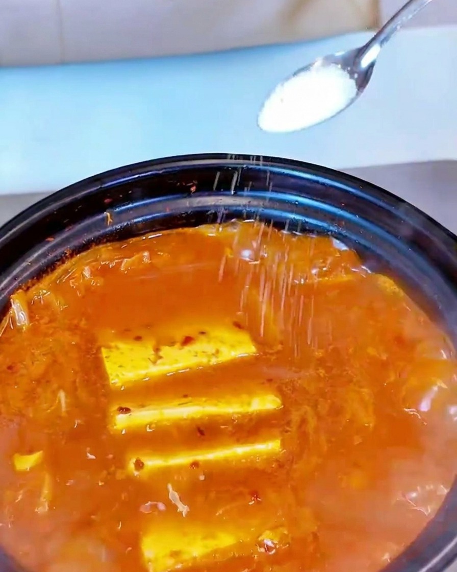 끓는 찌개 위에 소금을 약간 뿌려 간을 맞추는 모습