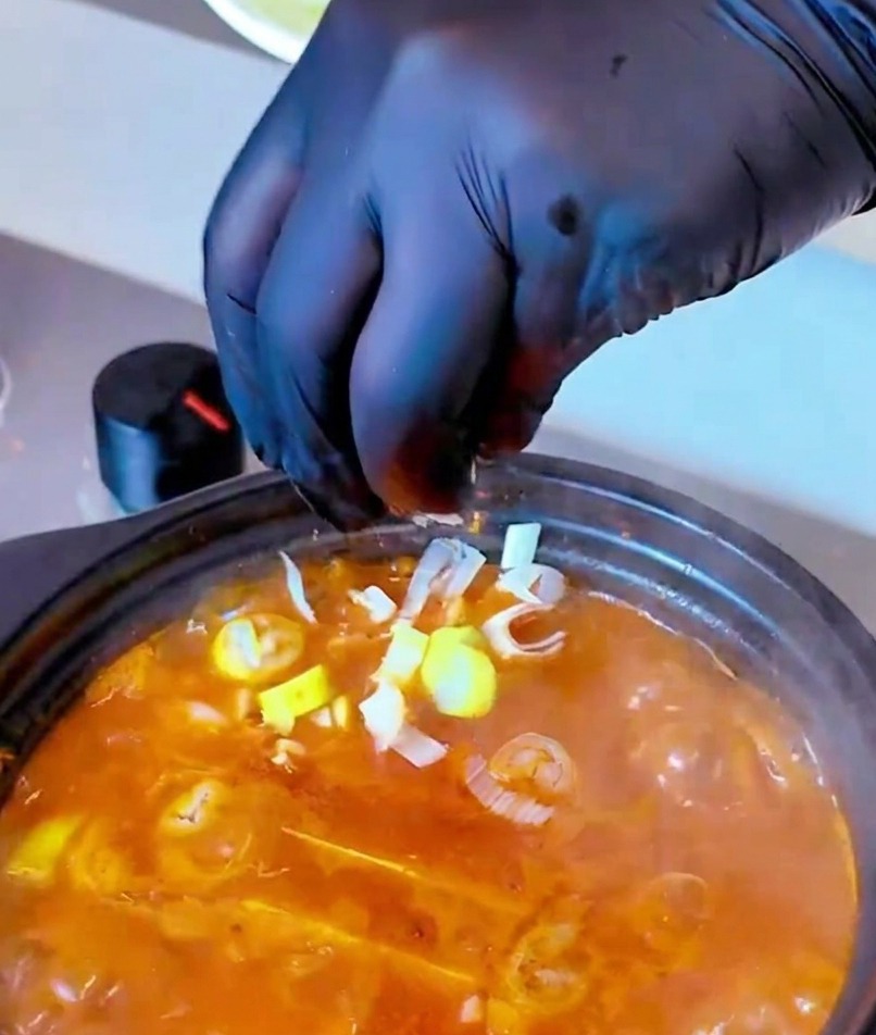 보글보글 끓는 찌개 위에 송송 썬 대파를 뿌리는 모습