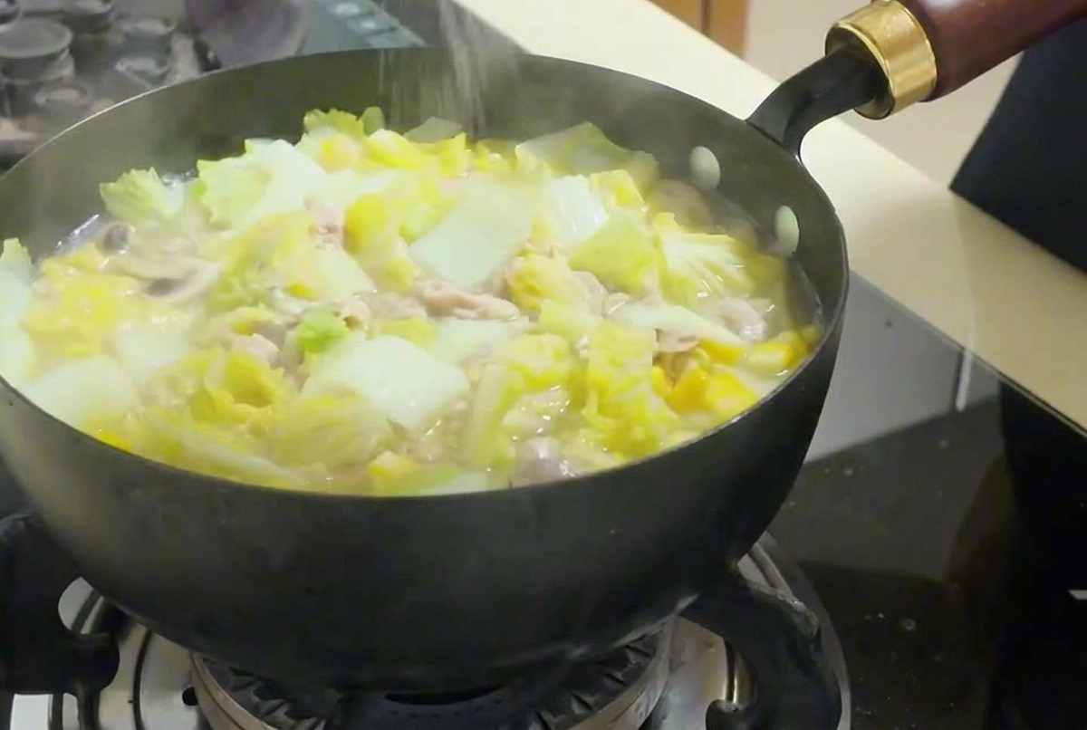 김치찌개 위로 소금을 가볍게 뿌려 간을 맞추는 모습.