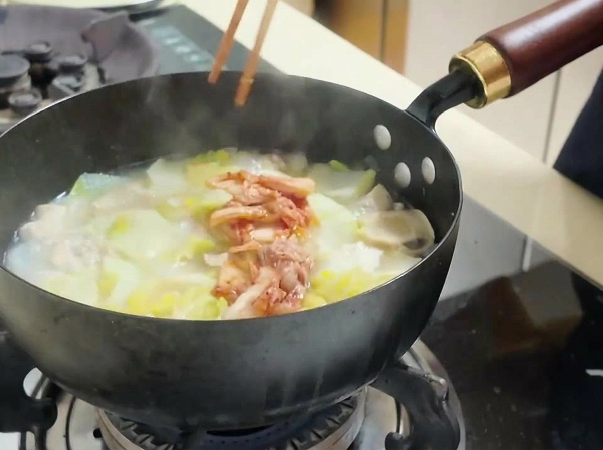 냄비 중앙에 잘게 썬 빨간 김치를 듬뿍 얹고 있는 모습.