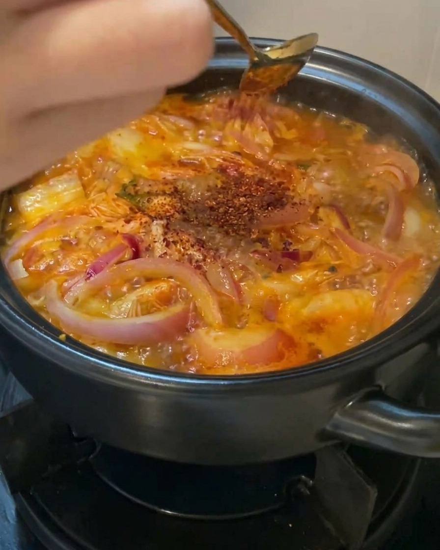 끓는 찌개 위에 붉은 고춧가루를 골고루 뿌리는 손길.