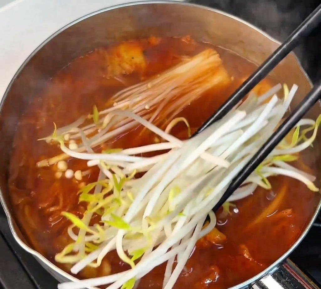 팽이버섯 옆으로 신선한 콩나물을 젓가락으로 집어 넣는 모습