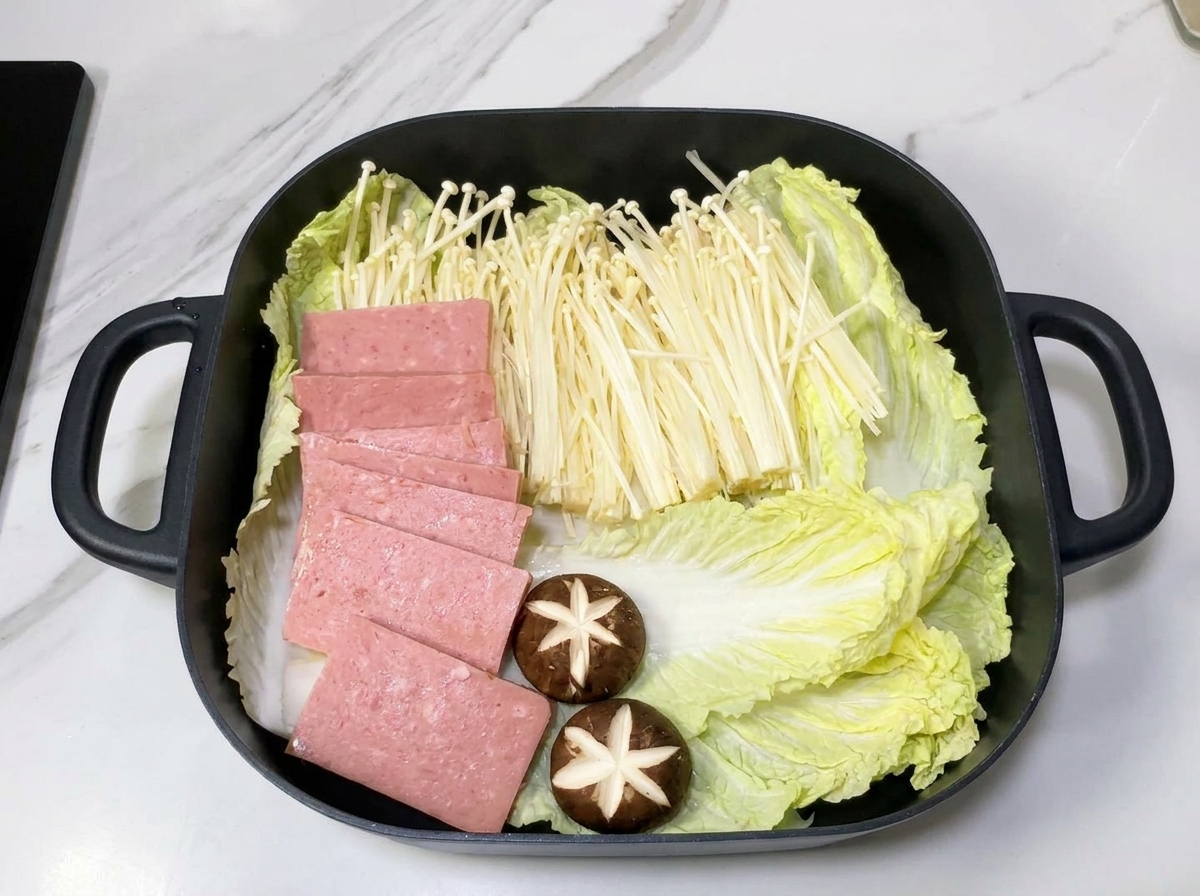 양파 위에 배추, 팽이버섯, 스팸을 구역을 나누어 가지런히 담은 냄비.