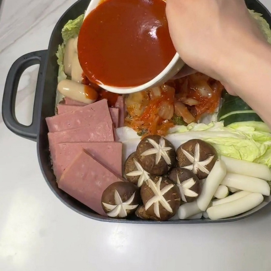 냄비 중앙의 재료 위로 미리 준비한 붉은 고추장 양념장을 붓는 모습.
