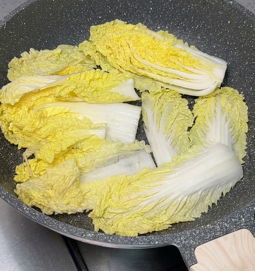 회색 전골 냄비 바닥에 큼직하게 썬 배추를 넉넉히 깔아둔 모습