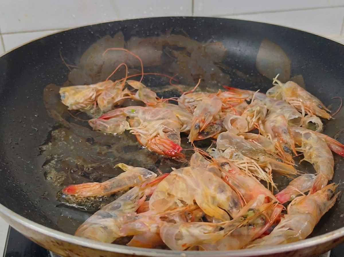 팬에서 식용유와 함께 주황색으로 변할 때까지 볶아지는 새우 껍질들