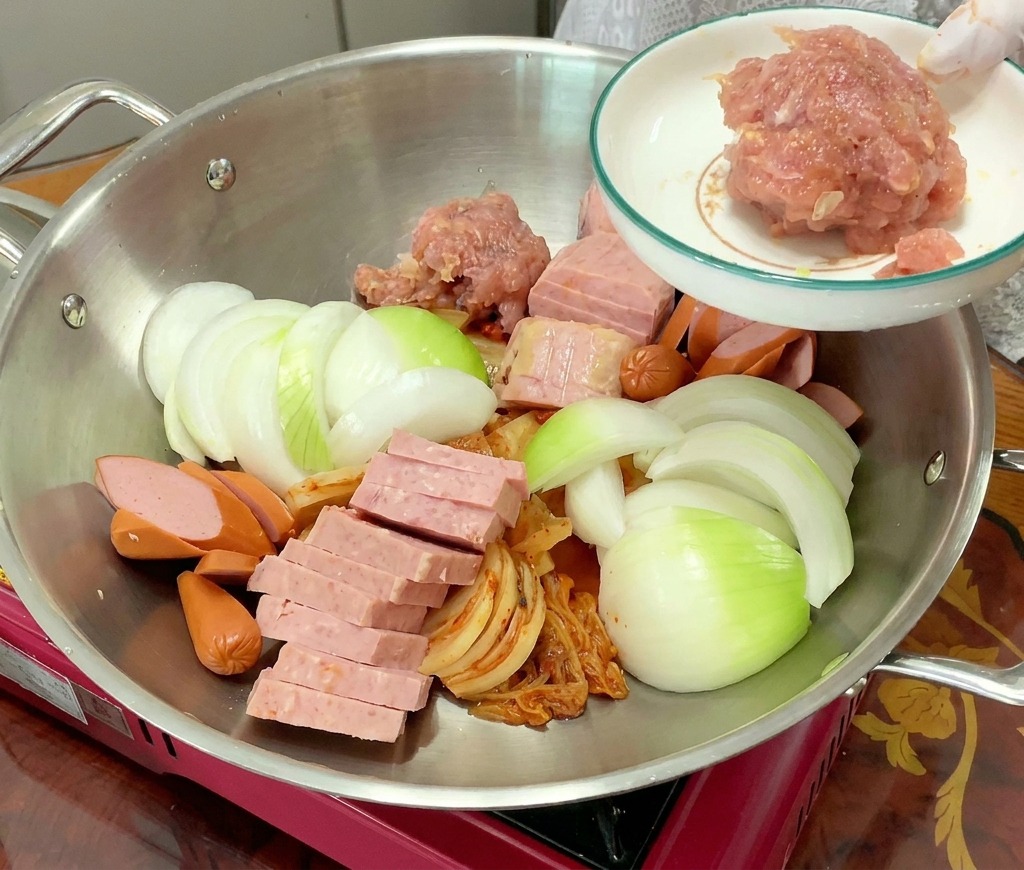 각종 재료가 세팅된 냄비 중앙에 양념된 다진 돼지고기를 얹는 모습.