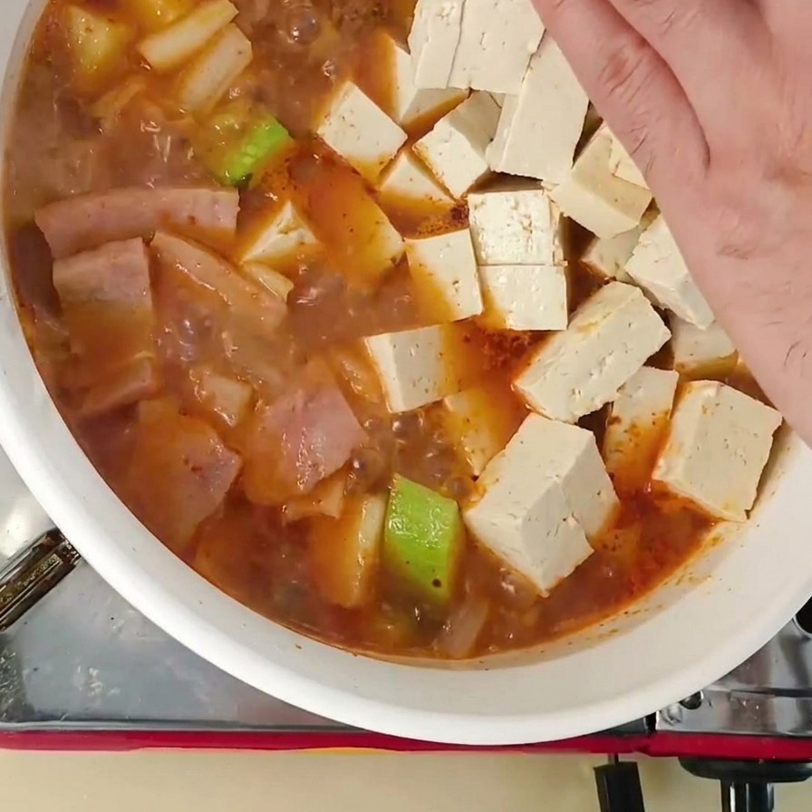 찌개에 하얀 두부 조각들을 조심스럽게 넣는 모습