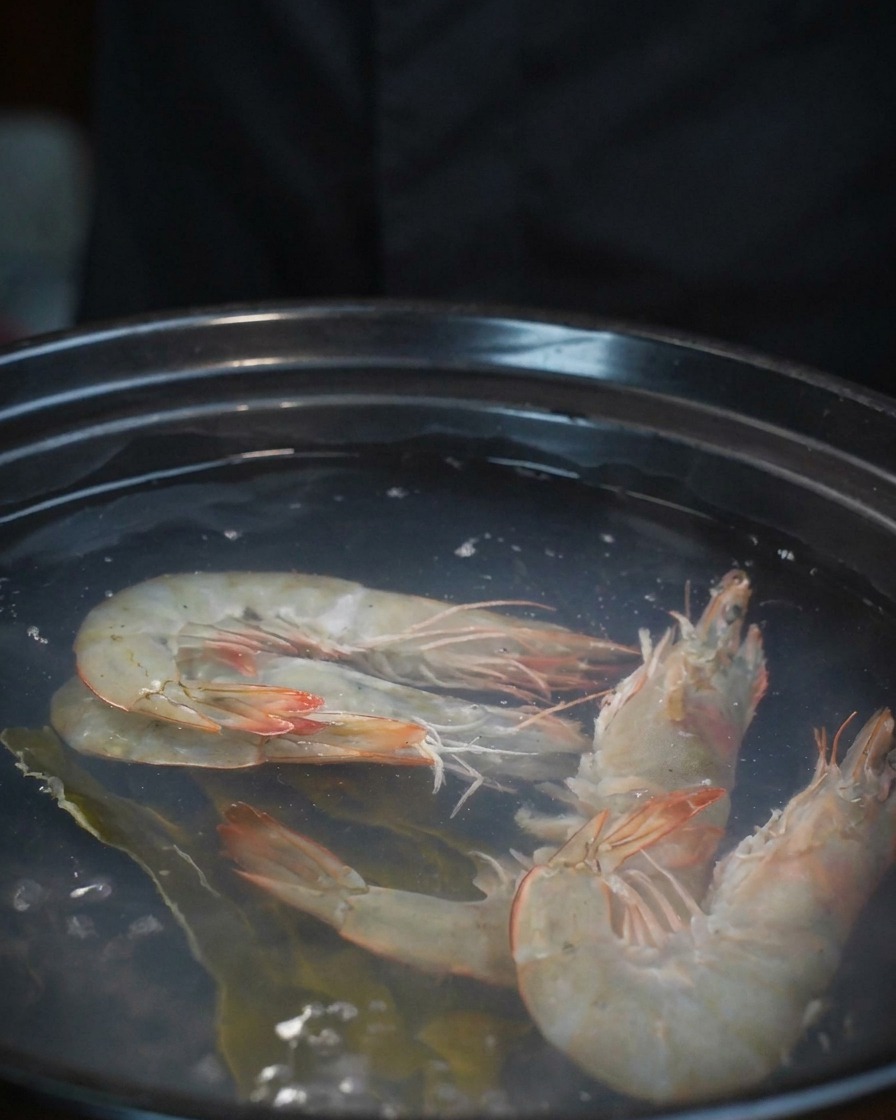 새우가 든 냄비에 신선한 바지락을 한 그릇 쏟아 넣는 모습.