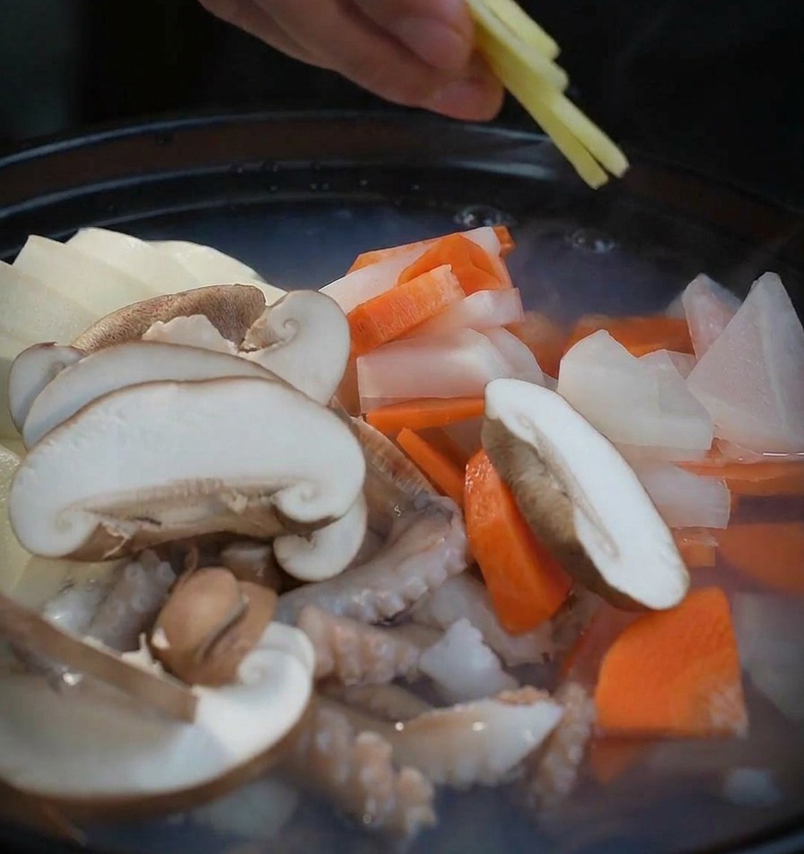 얇게 썬 생강을 찌개에 넣는 손길.