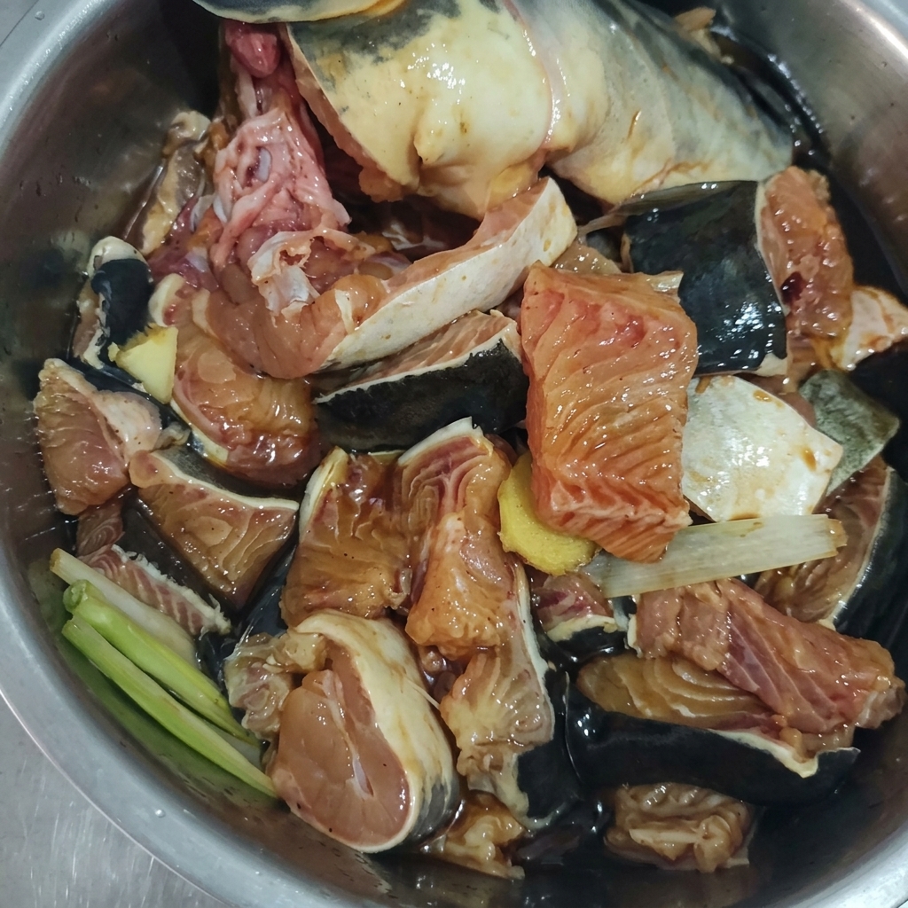 쪽파, 생강, 양념장과 함께 버무려진 메기 토막들.