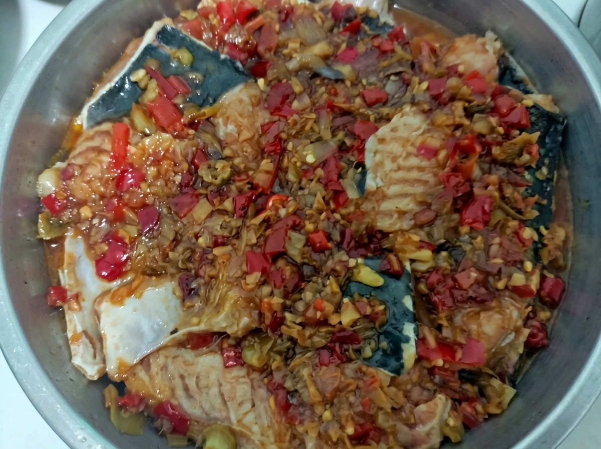 붉은 양념을 얹은 메기가 찜기 안에서 익어가는 모습.