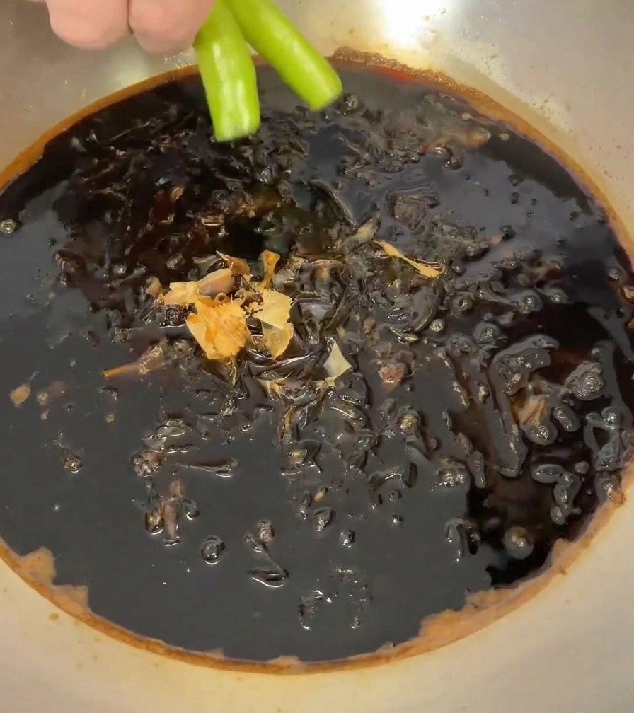 가쓰오부시가 담긴 소스에 초록색 청양고추 두 개를 넣는 모습.
