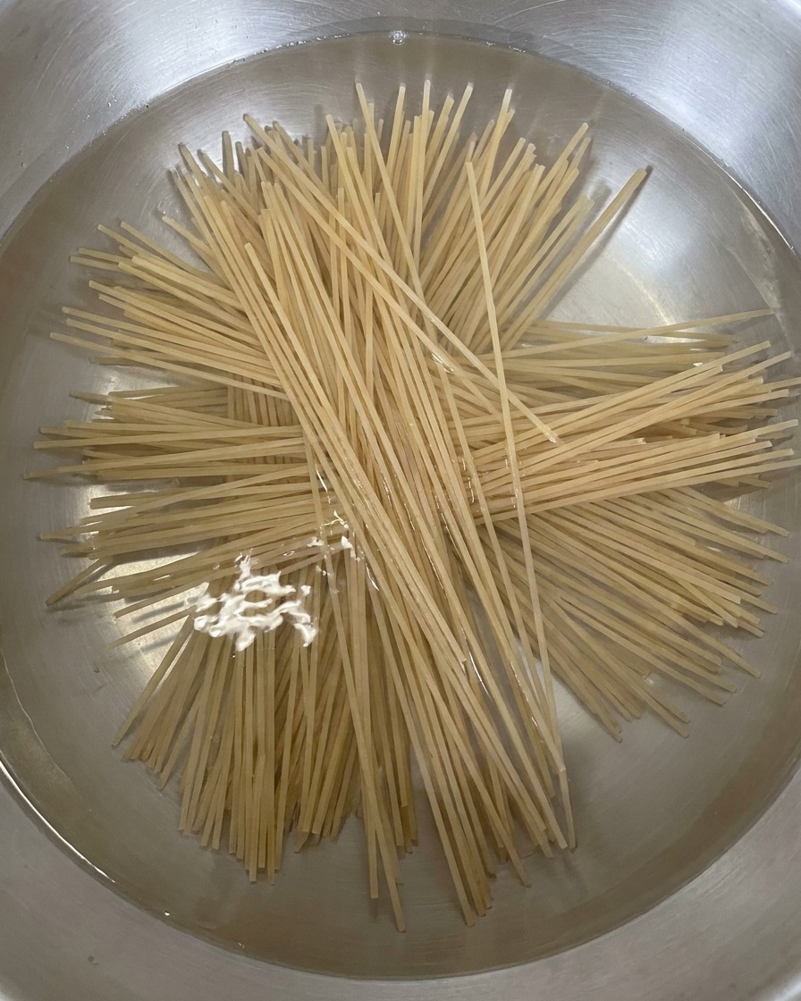 끓는 물이 담긴 냄비에 메밀면을 펼쳐서 넣는 모습.