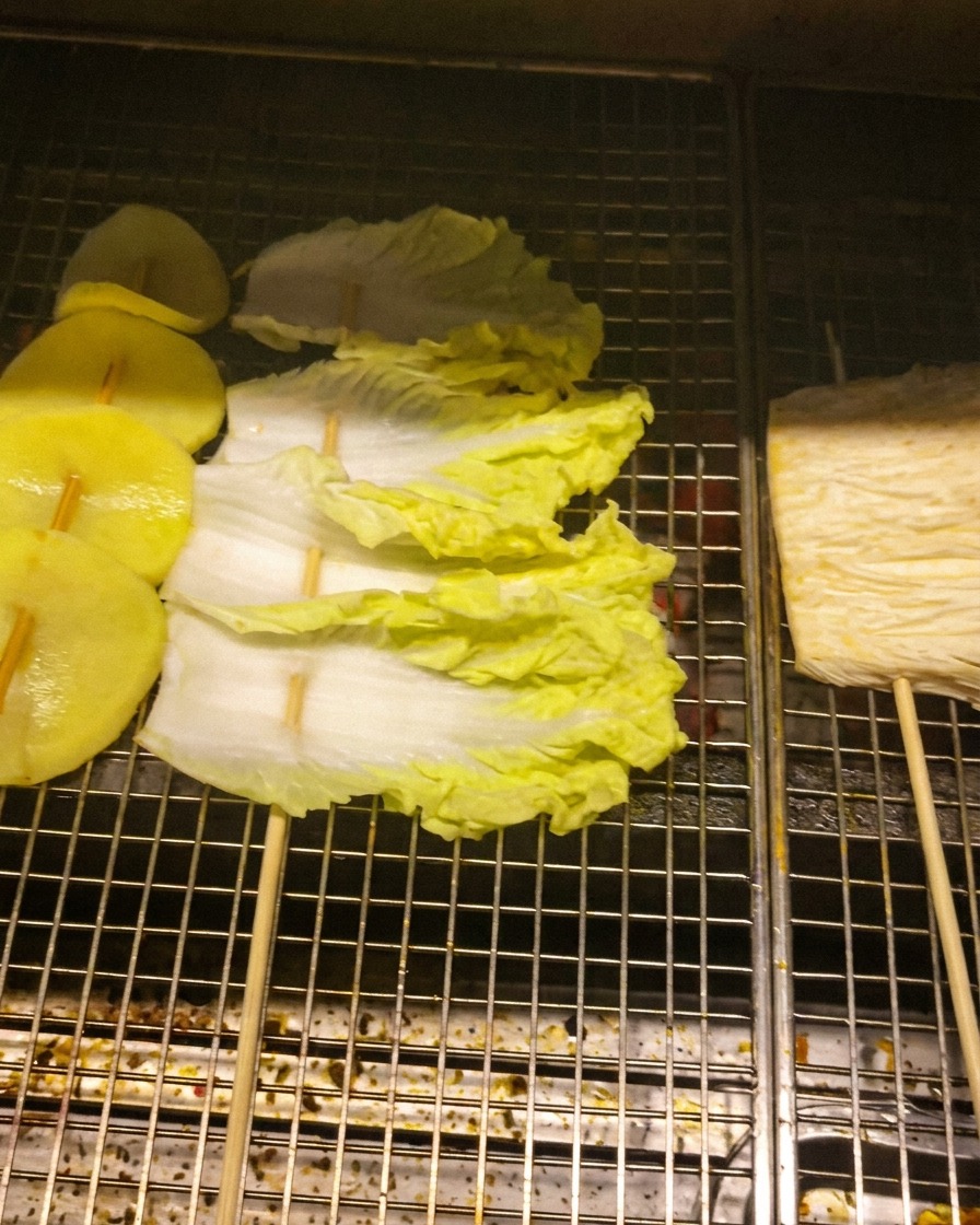 그릴 위에 감자, 배추, 팽이버섯 꼬치를 올려 굽는 모습