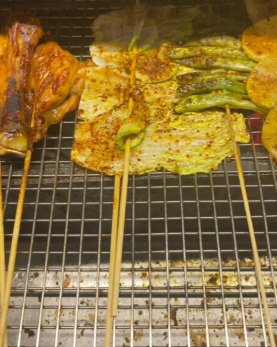 그릴 석쇠 위에서 익어가는 닭다리살, 알배기 배추, 애호박, 그린빈, 감자 슬라이스
